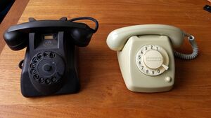 Two vintage rotary dial telephones.