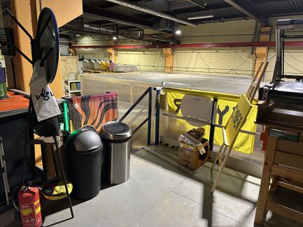 A photo showing the entrance to the space (looking down the stairs) with bins to the left of the stairs and cardboard to the right.
